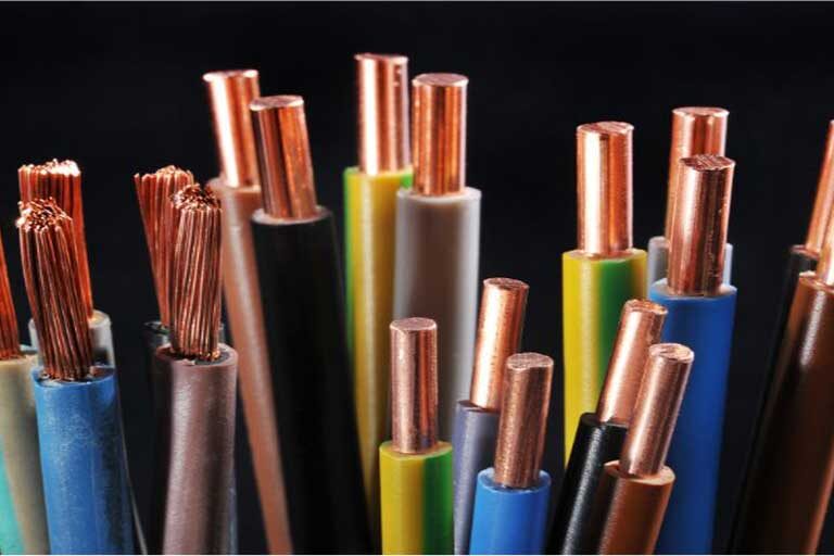 Diversas pontas de fios e cabos elétricos de diferentes cores (azul, verde, marrom, cinza, preto) agrupados verticalmente contra um fundo preto